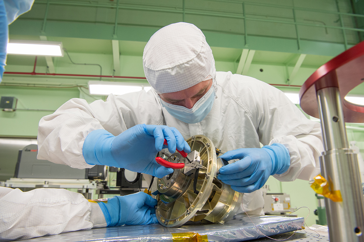 A NASA technician installs an optic reference cube to the HAM mechanism in order to perform alignment measurements
