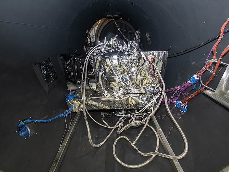 The OCI ETU rolls into the TVAC chamber. Lines are for electrical connections, temperature sensors, accelerometers, and liquid nitrogen, whic is used for cooling down the radiators.