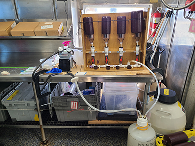 Filtering water to determine particulate absorption using high-performance liquid chromatography (HPLC) during a CalCOFI cruise.
