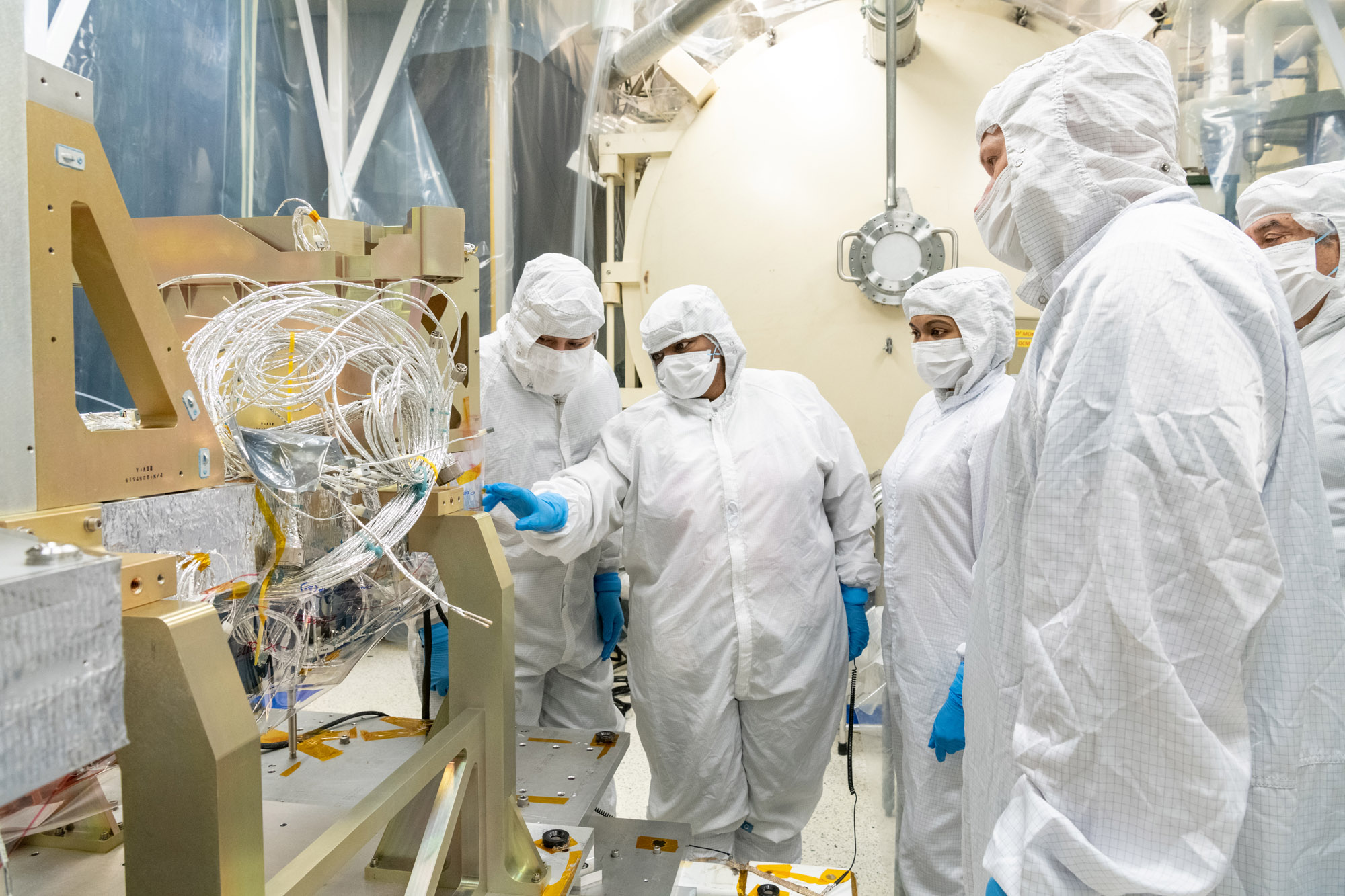 Blanket technicians discuss thermal templates on the Ocean Color Instrument Instrument Deck Structure (IDS) at Goddard Space Flight Center.