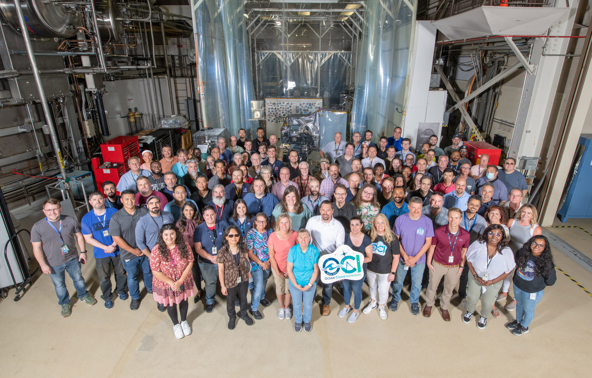 The Ocean Color Instrument (OCI) team poses with OCI and its integrated Earth Shade in June 2022 at Goddard Space Flight Center.