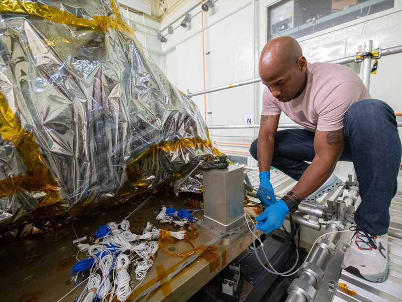 Technician Nathan Allen connects the purge line to the Ocean Color Instrument in preparation for X-Axis (vertical) vibration testing. Credit: Stover, Desiree