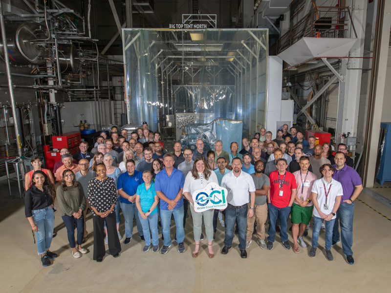 Ocean Color Instrument Team poses with the flight instrument behind them in a cleanroom tent on August 4, 2022. Credit: Stover, Desiree