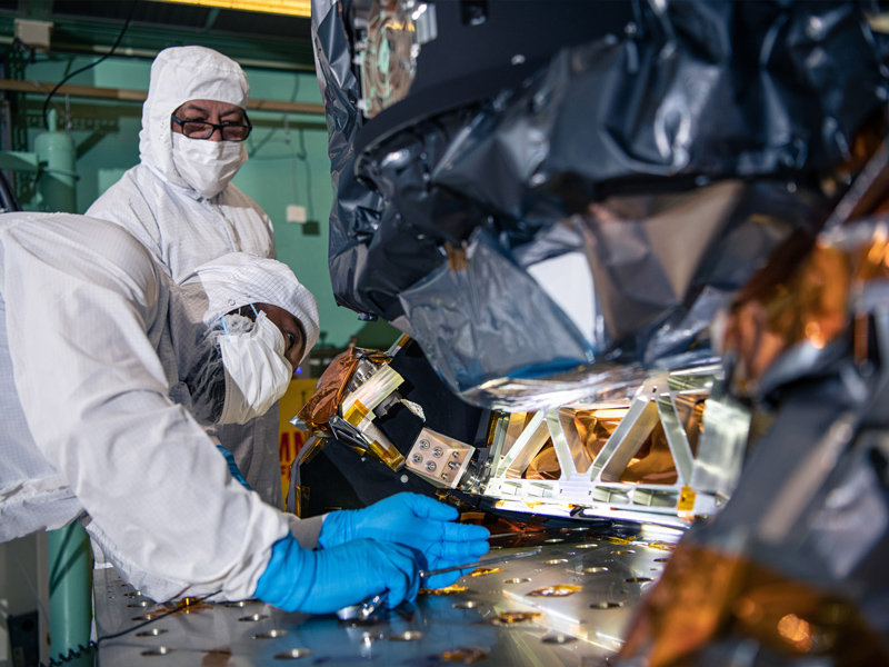 Quality engineer Luiz Mendez observes mechanical technician Tyere Garner remove bolts before lifting the Ocean Color Instrument from Tilt Mechanism to its ground support fixture. Credit: Henry, Dennis (Denny)
