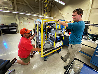Luke Ziemba and Michael Shook (LaRC) are shown working in the Naval Postgraduate School lab (Marina, CA) preparing their instrument for upload.  The LARGE "classic" suite of instrumentation measures in-situ aerosol microphysical and optical properties.