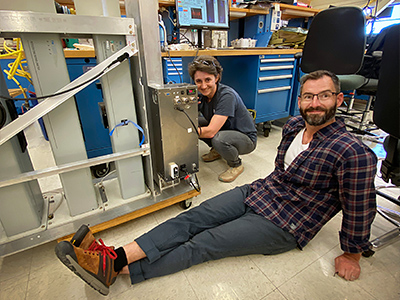 Cecile Carlson and Adam Ahern (NOAA CSL) are shown in the Naval Postgraduate School lab in Marina, CA. They are preparing their LiNeph instrument for upload. Laser nephelometry is a technique that measures how much light particles in the atmosphere scatter.