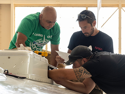Quality inspector Sam Habbal, mechanic Darick Alvarez and crew chief Juan Alverez work on the INMARSAT (communications) pod on the top of the NASA ER-2 at the NASA Armstrong Flight Research Center in Lancaster, CA.  
