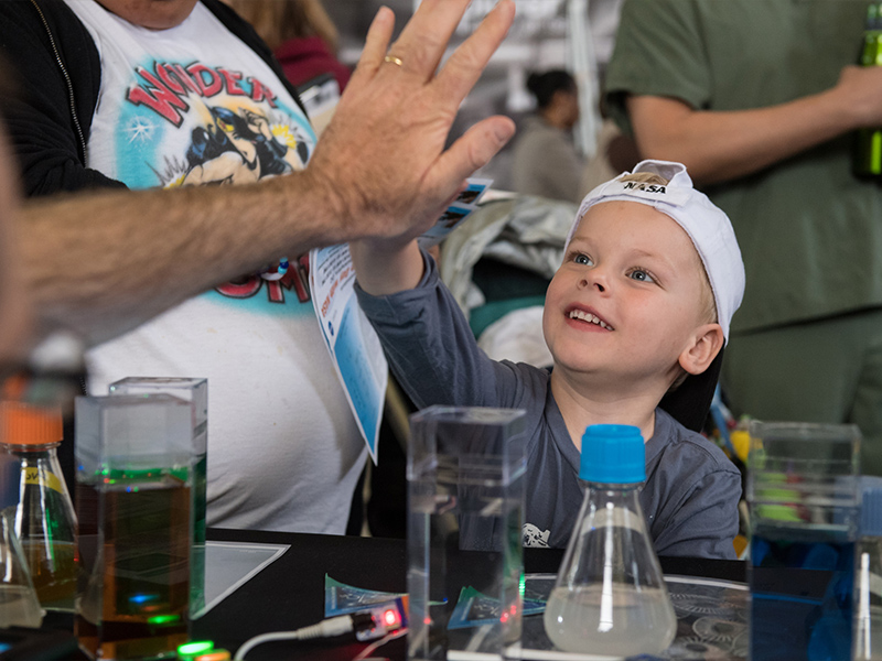 A visitor gives a high five after learning about phytoplankton at the PACE table at the Earth Day event at Union Station in Washington, D.C. Credit: Aubrey Gemignani (NASA)