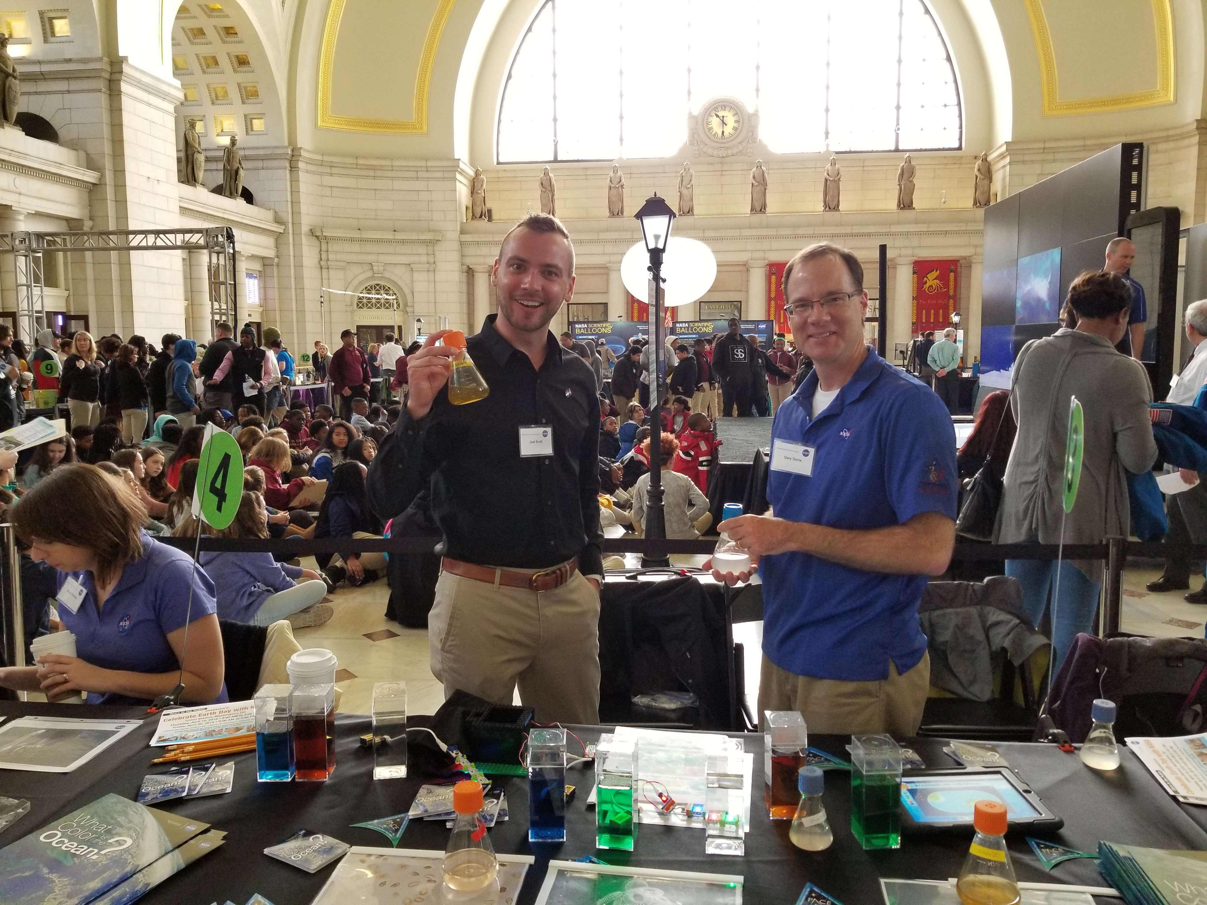 Joel Scott, scientific programmer (left), and Gary Davis, spacecraft systems engineer (right), showcase cultures of phytoplankton for NASA Earth Day Celebration at Union Station in Washington D.C.