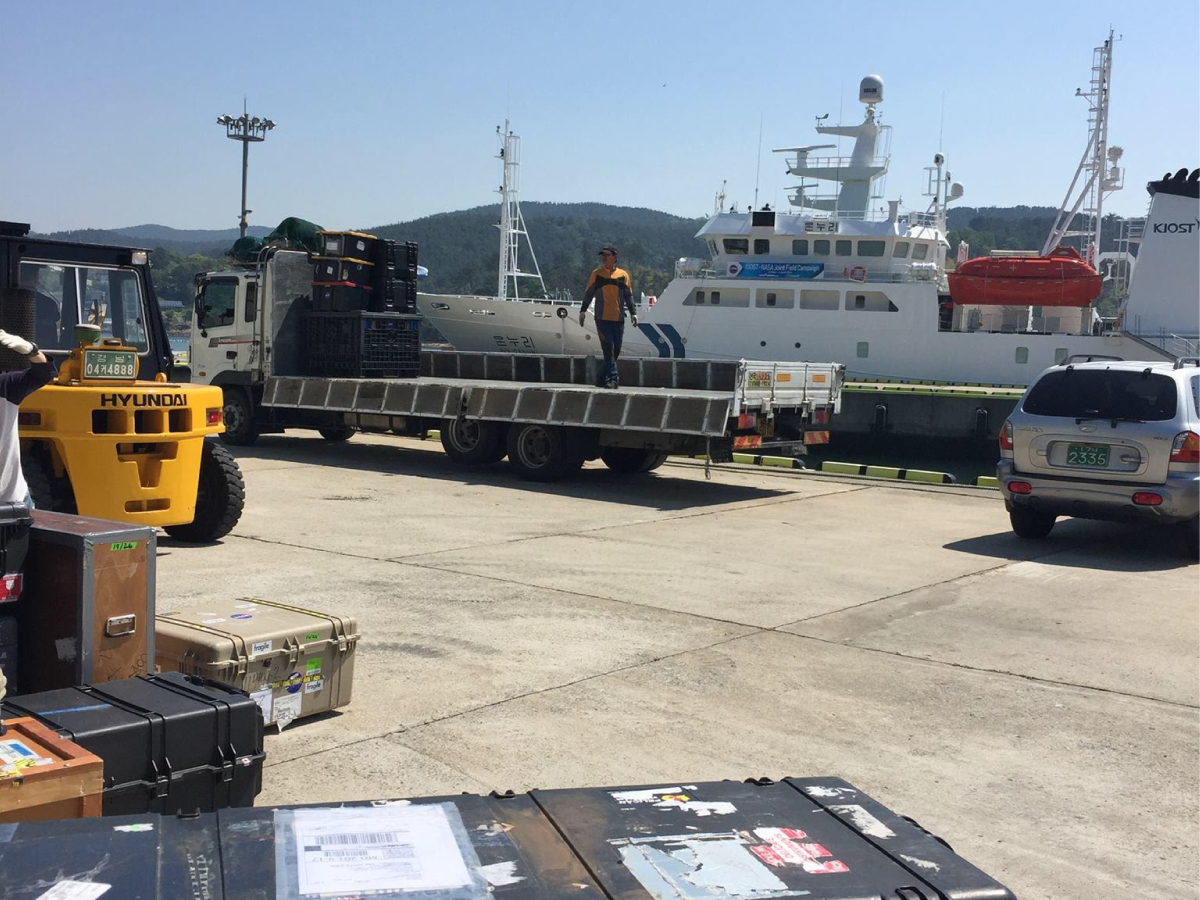 Multiple vehicles bearing scientific equipment queue for boarding