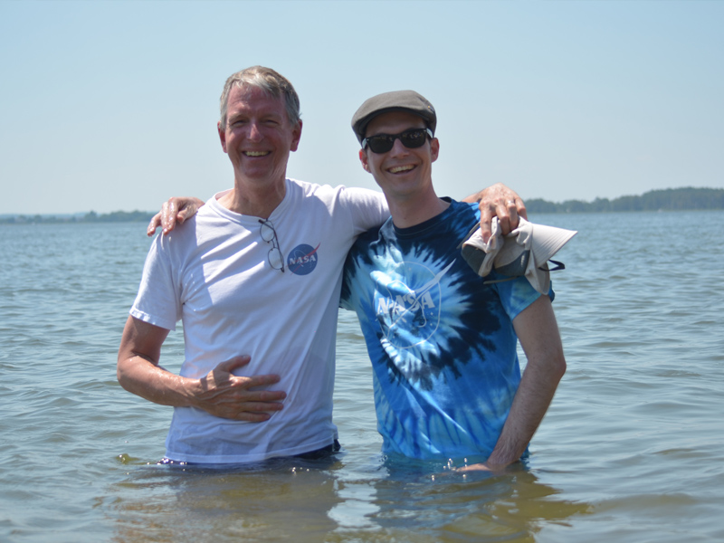 Ocean color scientists Norman Kuring (left) and Lachlan McKinna (right) wade waist-deep into the Chesapeake Bay to measure the "Sneaker Depth" of the water - the depth where a pair of white sneakers can no longer be seen. Credit: NASA GSFC