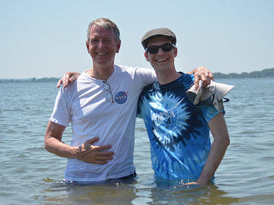 Ocean color scientists Norman Kuring (left) and Lachlan McKinna (right) wade waist-deep into the Chesapeake Bay to measure the "Sneaker Depth" of the water - the depth where a pair of white sneakers can no longer be seen. Credit: NASA GSFC